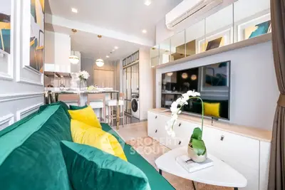 Modern living room with green sofa, stylish decor, and open kitchen layout in a contemporary apartment.