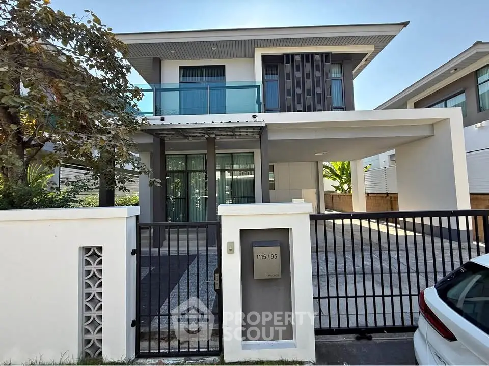 Modern two-story house with sleek design and gated driveway in a suburban neighborhood.