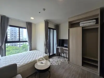 Modern bedroom with large windows and balcony access in urban apartment