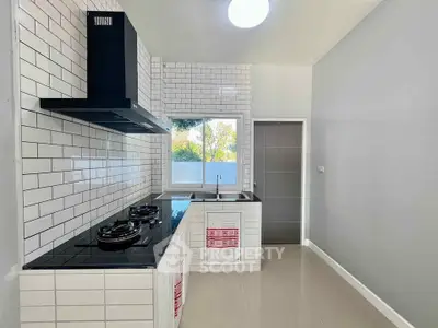 Modern kitchen with sleek black appliances and white subway tiles, featuring a gas stove and ample natural light.