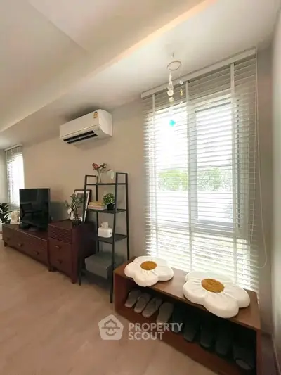 Stylish living room with modern decor, air conditioning, and ample natural light through large windows.