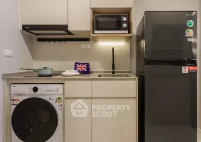 Modern compact kitchen with appliances including washing machine, microwave, and fridge.