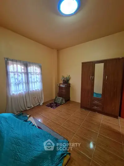 Cozy bedroom with wooden wardrobe and tiled flooring, featuring soft lighting and a window view.
