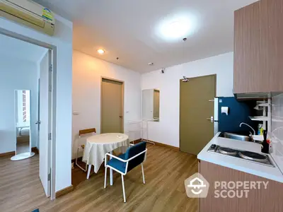 Bright and cozy apartment interior with modern kitchen, compact dining area, and wooden flooring, perfect for singles or couples.