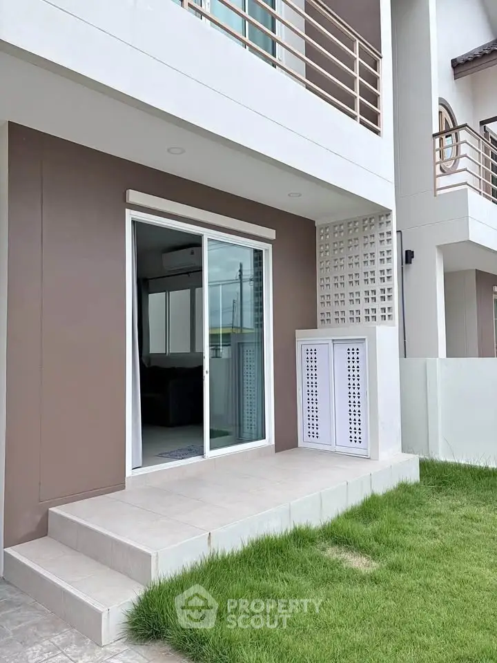 Modern townhouse exterior with sliding glass doors and small lawn area, perfect for urban living.