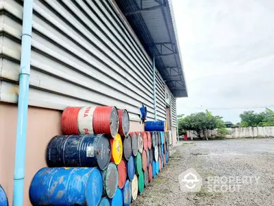 Industrial warehouse exterior with stacked barrels and spacious gravel yard