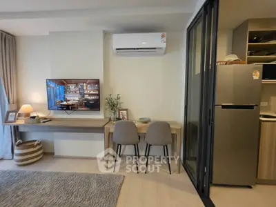 Modern living room with stylish decor, air conditioning, and a sleek kitchen area.