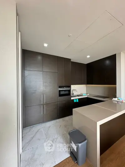 Modern kitchen with sleek dark cabinets and marble flooring