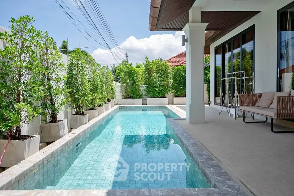 Luxurious private pool area with lush greenery and modern patio seating, perfect for relaxation and entertainment.