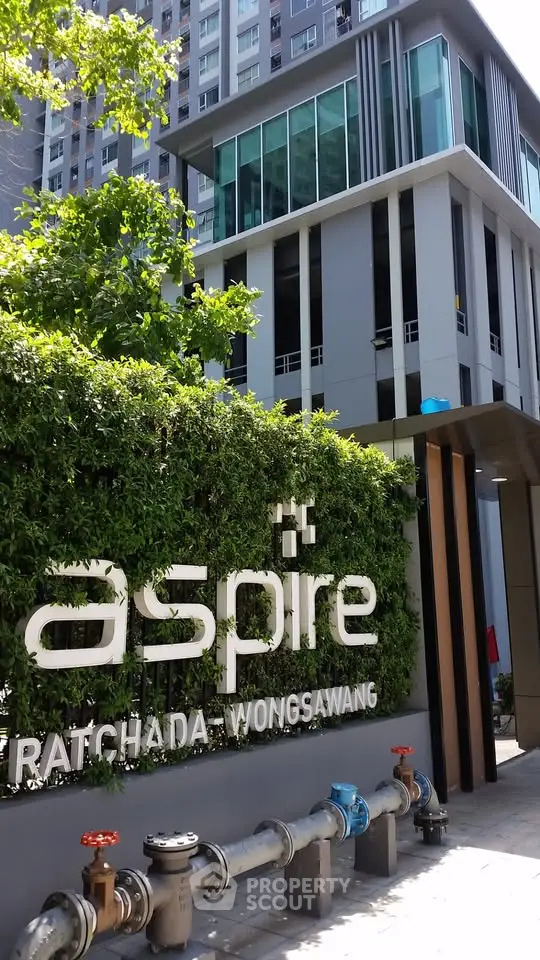 Modern condominium building with lush greenery and stylish architecture at Aspire Ratchada Wongsawang.