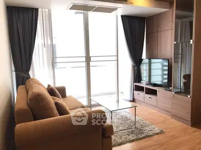 Modern living room with cozy sofa, glass coffee table, and large TV, featuring floor-to-ceiling windows and elegant curtains.