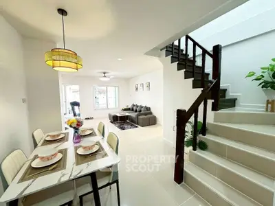 Modern open-plan living and dining area with stylish staircase and elegant decor.