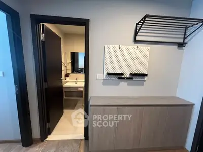Modern apartment entryway with bathroom view and sleek storage solutions.