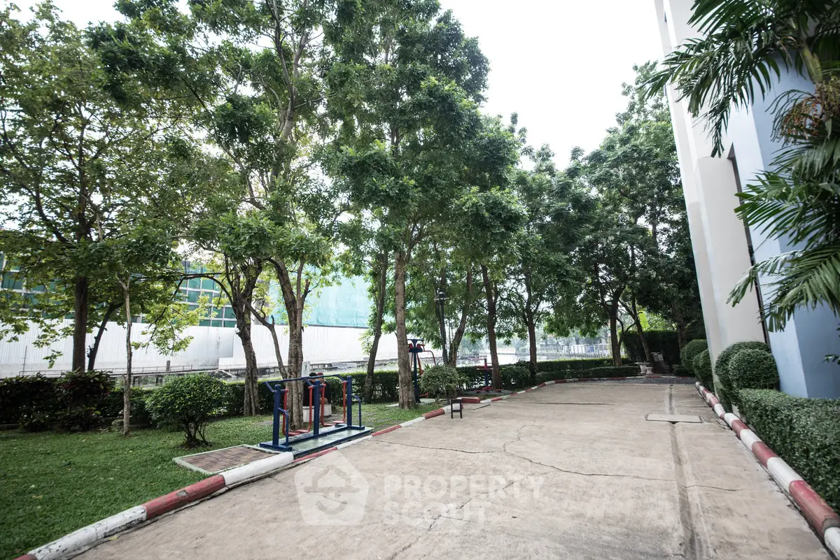 Serene outdoor garden area with lush greenery and exercise equipment in a residential complex.