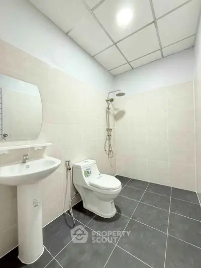 Modern minimalist bathroom with sleek fixtures and tiled flooring.