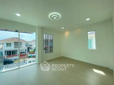 Bright and spacious room with large windows and modern lighting in a suburban home.