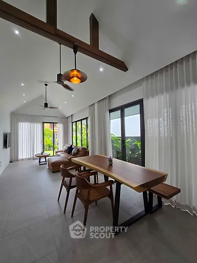 Spacious modern living room with high ceilings, elegant furniture, and large windows offering lush garden views.
