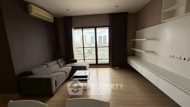 Spacious modern living room with city view, featuring sleek furniture and large windows.