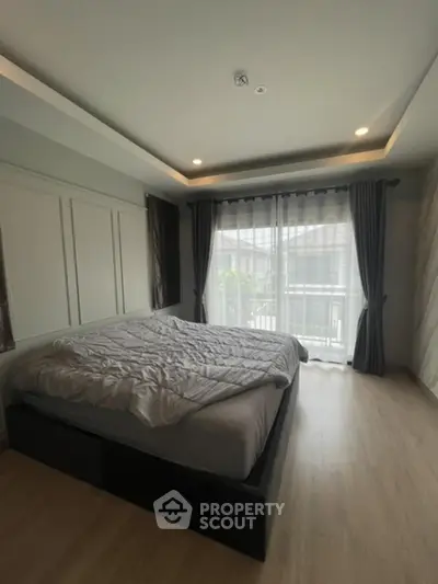 Spacious bedroom with modern design, large bed, elegant dark curtains, and ample natural light from floor-to-ceiling windows, perfect for a restful retreat.