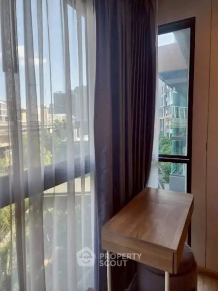 Chic urban apartment with stylish corner desk and city view through large windows.