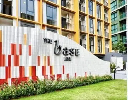 Modern apartment building exterior with colorful facade and lush green landscaping.