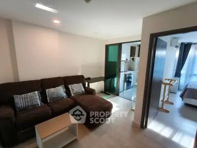 Modern living room with cozy brown sofa and open layout leading to kitchen and bedroom.