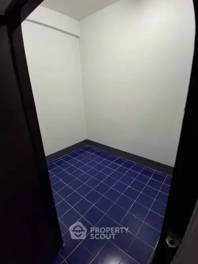 Compact storage room with blue tiled floor and white walls, ideal for organizing essentials.