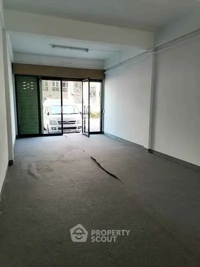 Spacious empty room with large glass doors and carpet flooring, ideal for office or retail space.