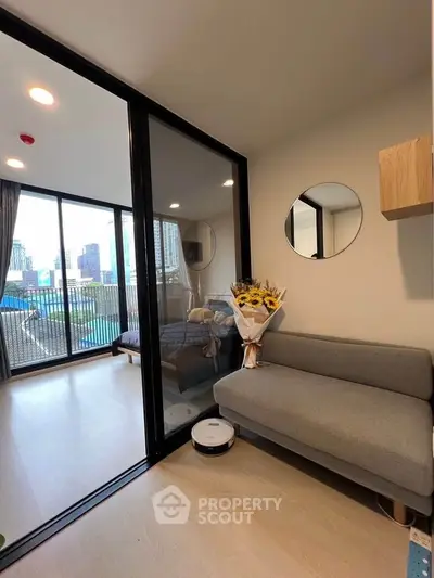 Modern apartment with glass partition, cozy sofa, and city view balcony.