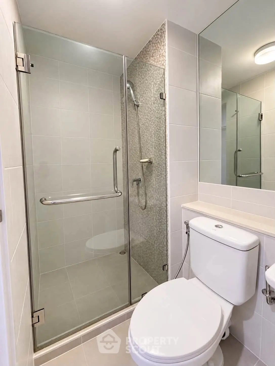 Modern bathroom with glass shower enclosure and sleek fixtures in a contemporary apartment.