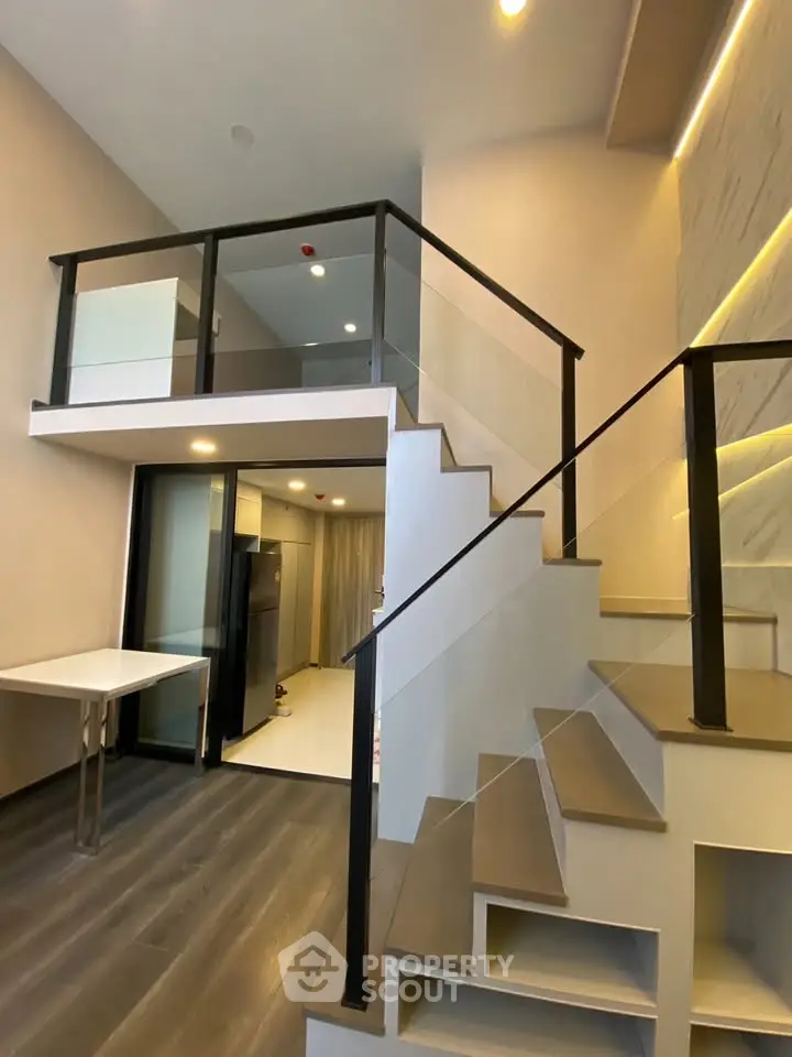 Modern duplex apartment with sleek staircase and open layout, featuring high ceilings and contemporary design.
