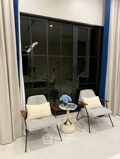 Elegant living room with modern chairs and large window, perfect for relaxation.