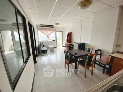 Spacious living room with dining area and large windows offering natural light.