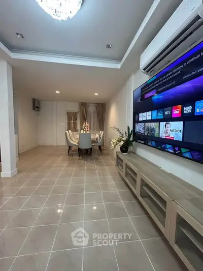 Spacious living room with modern TV setup and elegant dining area, perfect for entertainment and relaxation.