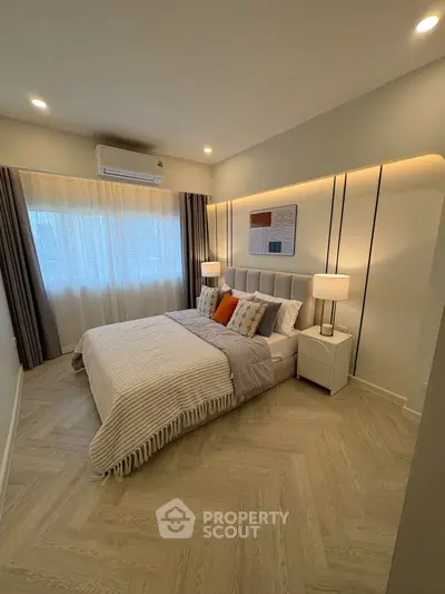 Modern bedroom with stylish decor and natural light, featuring a cozy bed and elegant lighting.