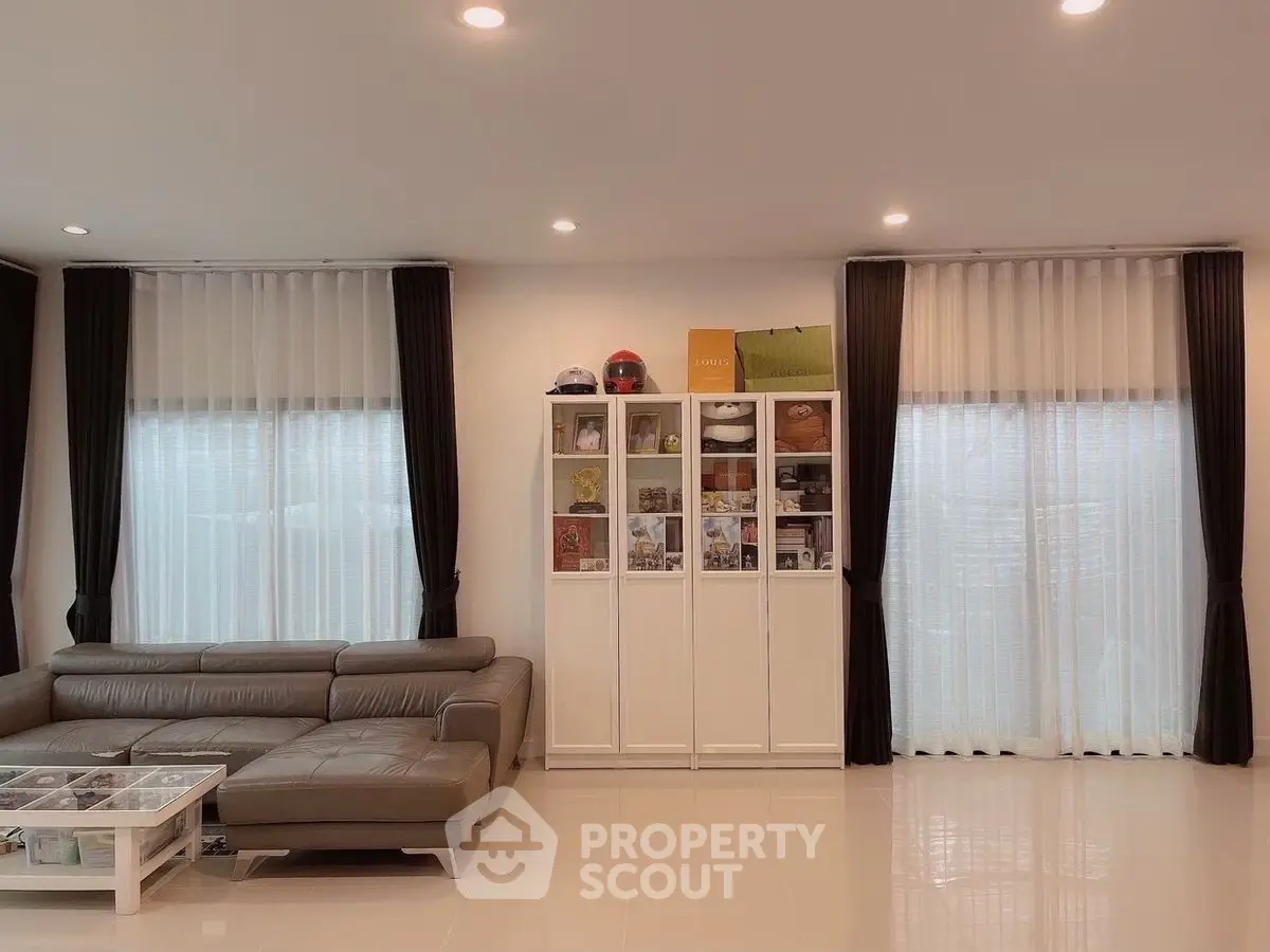 Spacious modern living room with sleek leather sofa and elegant display cabinet.