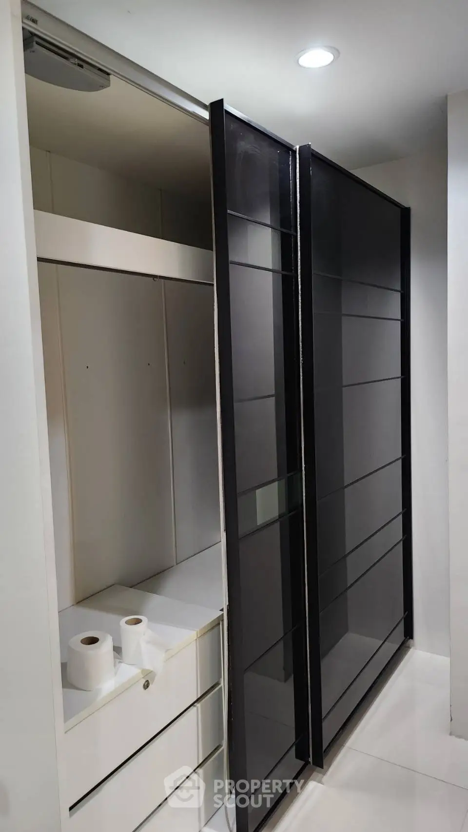 Modern storage closet with sliding glass doors and sleek white drawers.
