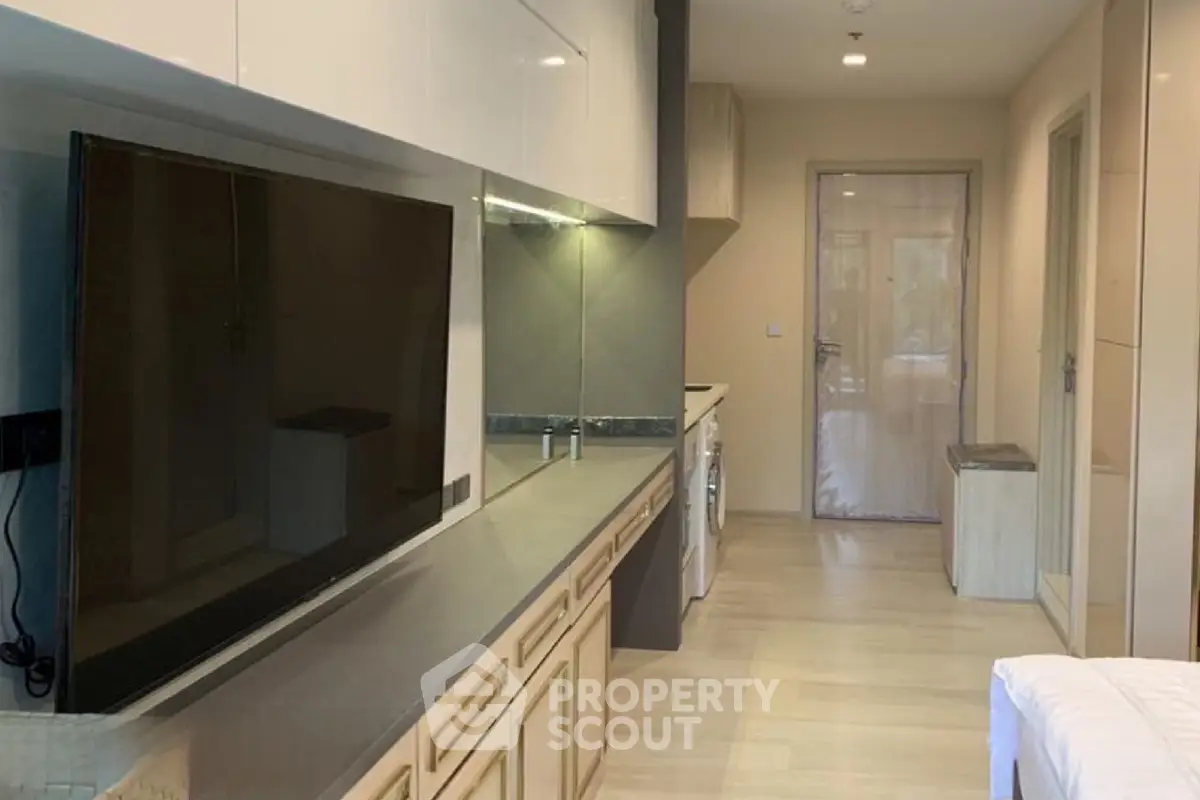 Modern studio apartment with sleek kitchen and large TV, perfect for urban living.
