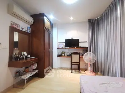 Cozy bedroom with wooden furniture and study area, featuring a wall-mounted TV and air conditioning.