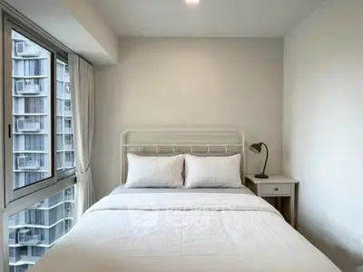 Cozy bedroom with large window offering city views, featuring a comfortable bed and modern decor.