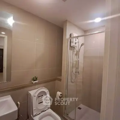 Modern bathroom with sleek shower and toilet in contemporary apartment.