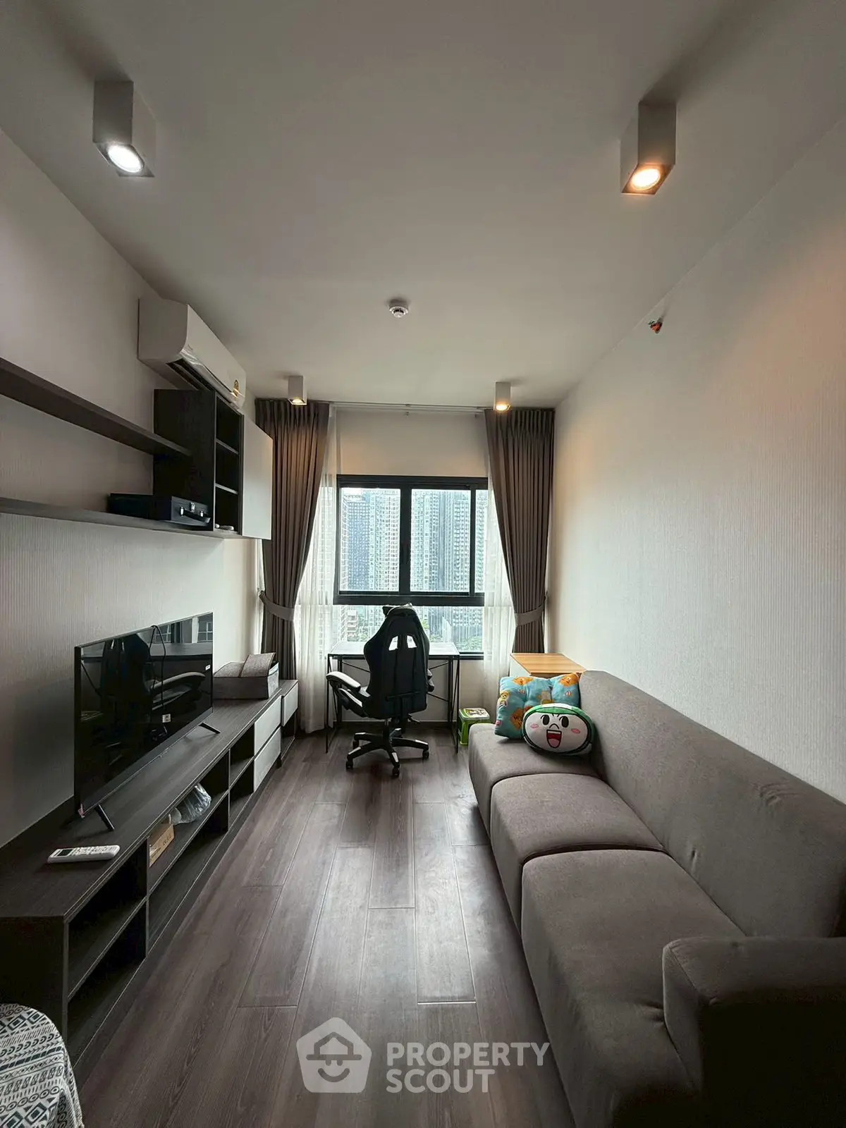 Modern living room with city view, featuring sleek furniture and cozy ambiance.
