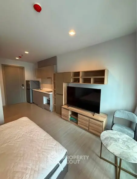 Modern studio apartment with sleek furniture and compact kitchen area, perfect for urban living.