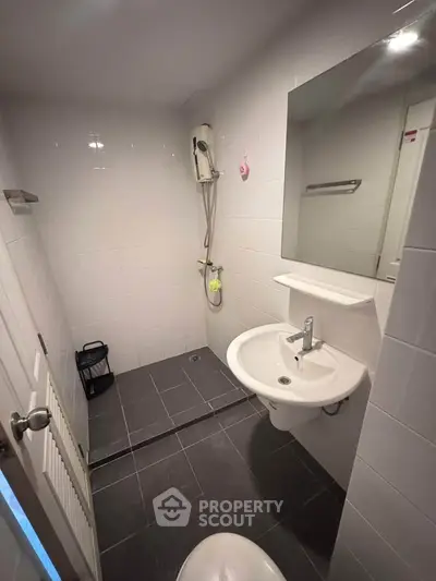 Modern bathroom with sleek fixtures and minimalist design, featuring a shower and stylish sink.