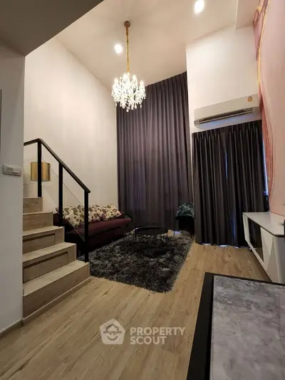 Modern living room with high ceiling, elegant chandelier, and cozy seating area.