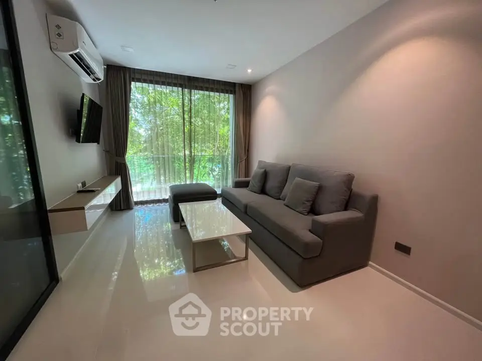 Modern living room with sleek furniture and large window offering lush green views.