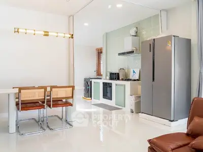 Modern kitchen with open layout and dining area, featuring sleek appliances and stylish decor.