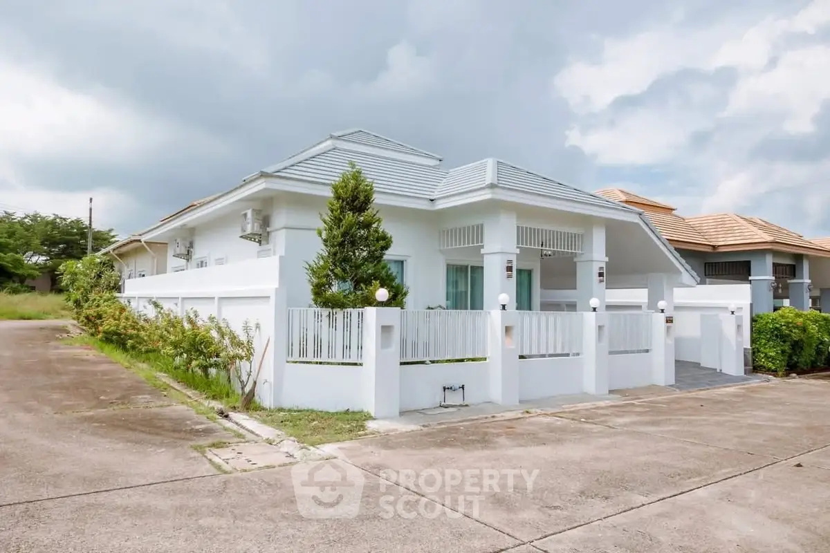 Charming single-story white house with modern design and spacious driveway in serene neighborhood.