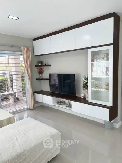 Modern living room with sleek built-in entertainment unit and large window for natural light.