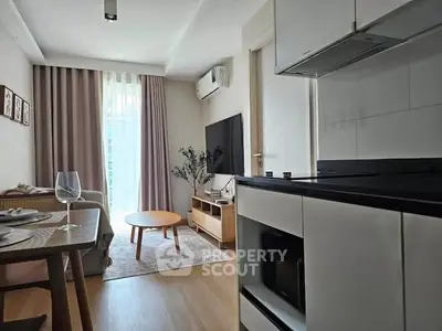 Modern living room with open kitchen, featuring sleek furniture and natural light.